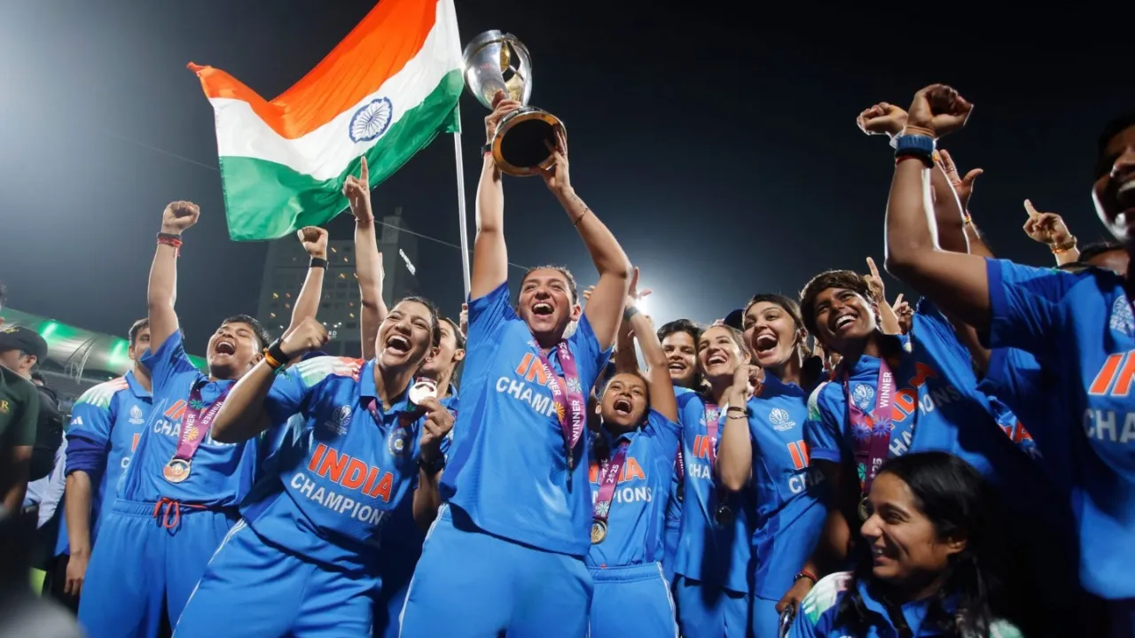 The Indian women’s cricket team is celebrating victory with the championship trophy and the national flag after winning an international cricket tournament.