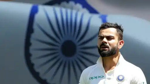 Virat Kohli wearing Team India Test jersey with the Indian flag's Ashoka Chakra blurred in the background