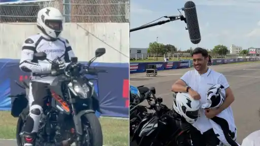 MS Dhoni wearing a racing helmet and riding gear, posing with a superbike on a Chennai racetrack