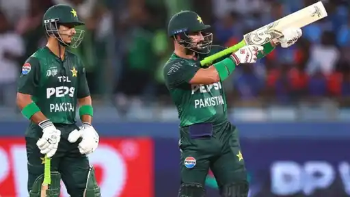 Two Pakistan batters in green kit, one raising his bat after a shot, during an Asia Cup match