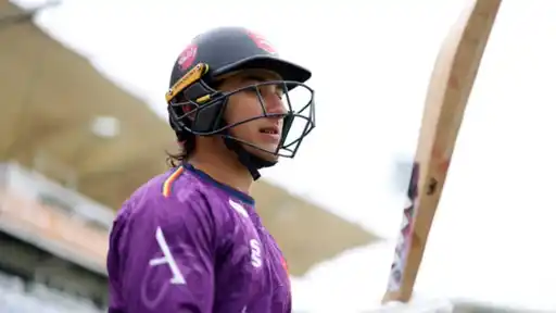 Robin Das in batting gear, helmet on, looking on during a match