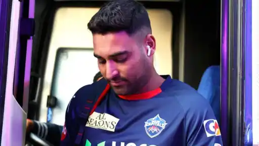 Vipraj Nigam in a Delhi Capitals jersey and earbuds stepping off a team bus