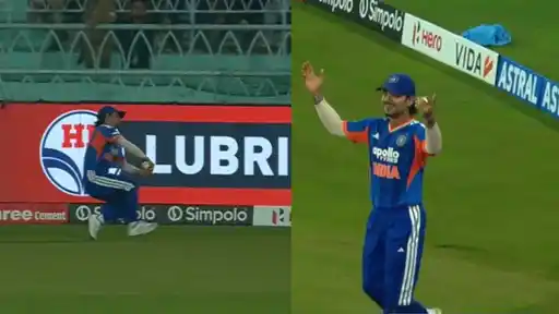 Ishan Kishan near the boundary boards, holding the ball against his body after a catch, then smiling with arms raised in celebration