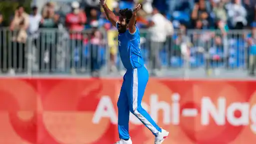 Jasprit Bumrah in India's blue kit raises both arms in celebration after taking a wicket against Sri Lanka in the Asian Games 2026 semifinal