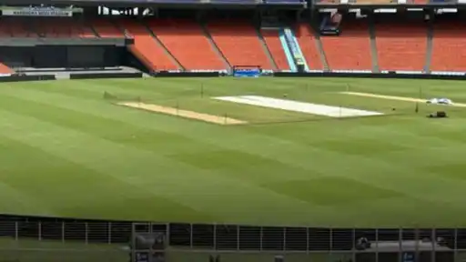 Empty Narendra Modi Stadium in Ahmedabad with orange seats and a green outfield, where a bomb threat email was received during the India U19 vs Australia U19 Youth Test
