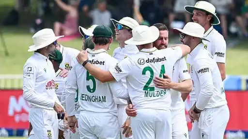 South Africa players in white Test kit gather in a huddle and celebrate on the field